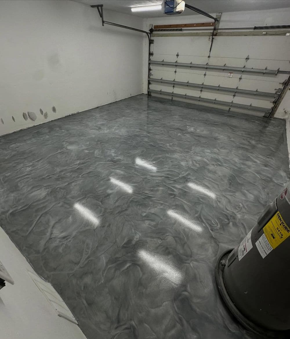 Epoxy-coated garage floor with a shiny gray marbled finish and overhead lighting.