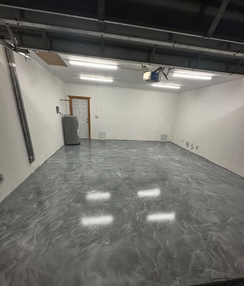 Empty garage with polished gray epoxy floor and white walls, well-lit with overhead lights.