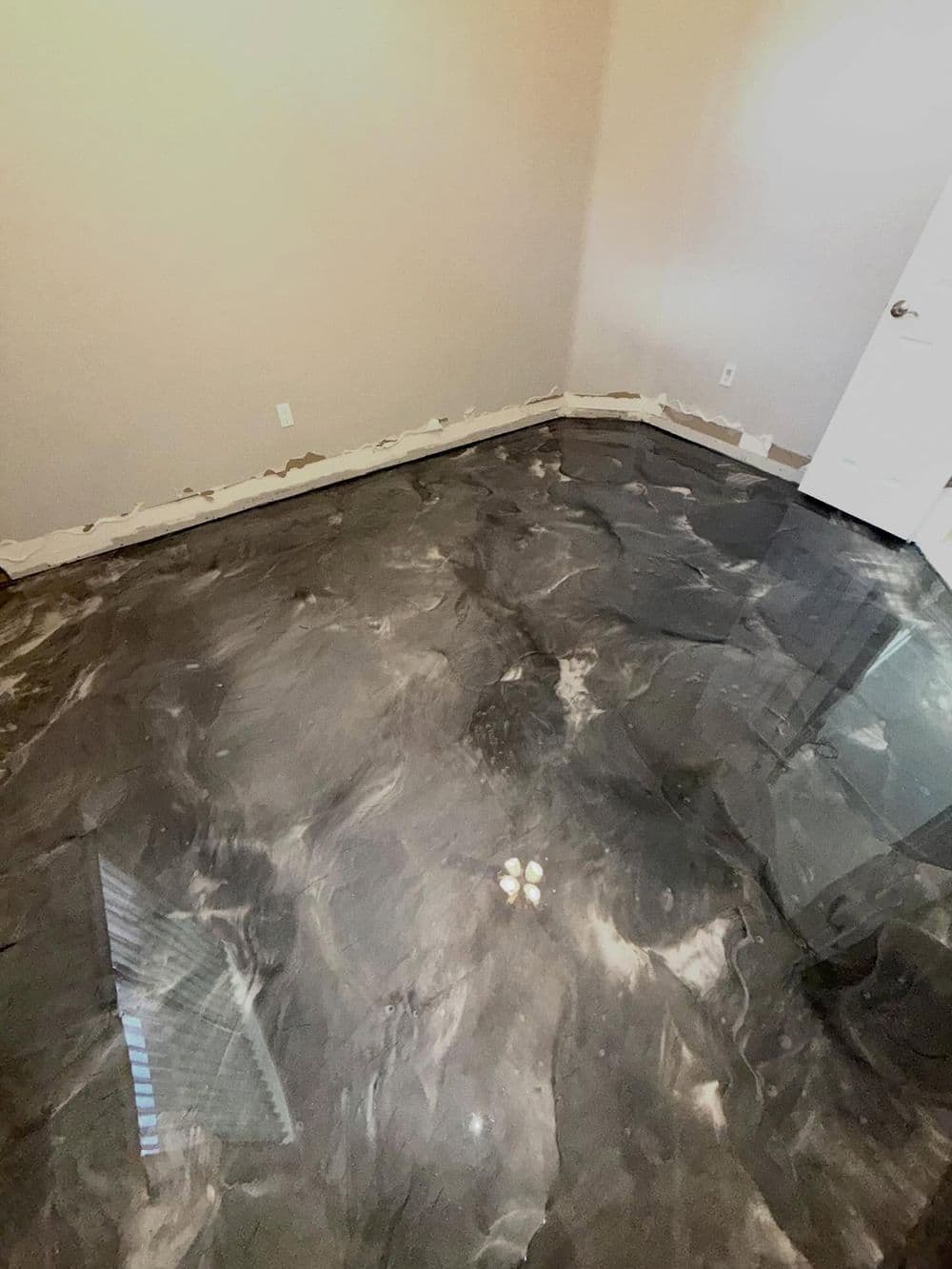 Newly installed marble epoxy floor in a room with unfinished wall edges and door.