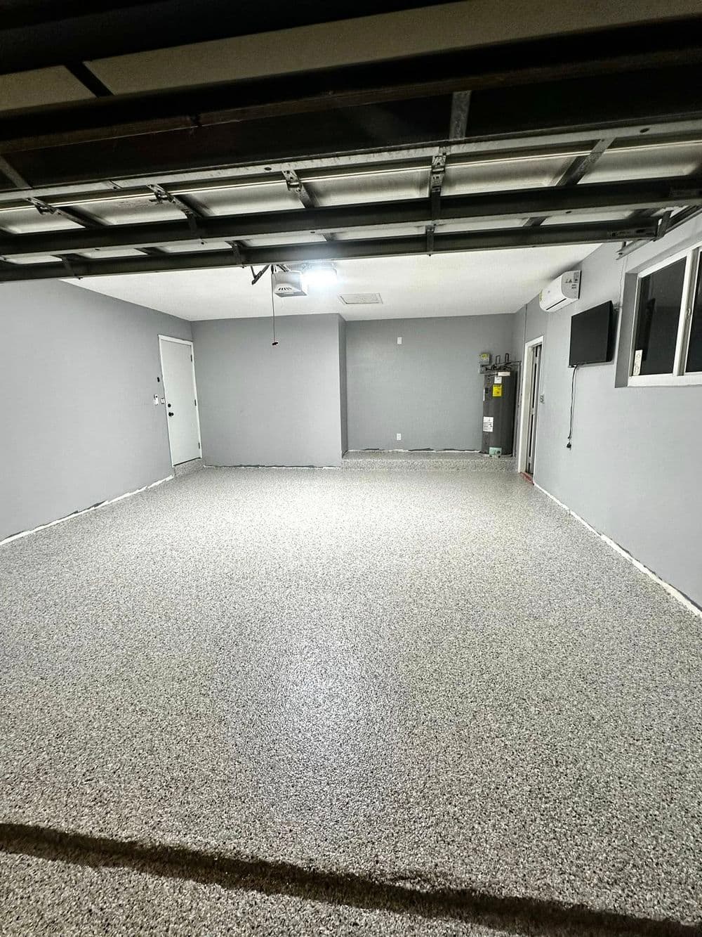 Clean, spacious garage with gray walls and textured epoxy-coated floor in modern design.