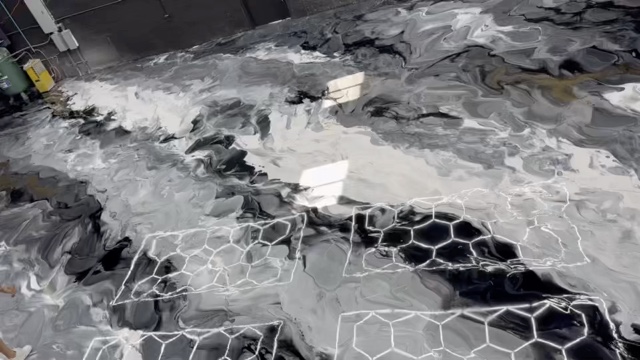 Close horizontal view of a gray, white and black metallic epoxy floor with white hexagon line inlays and a high-gloss finish